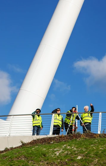 Wide-angle view of the Stockingfield Bridge with a group of students and lecturers in high-visibility vests conducting a surveying exercise on the platform beneath a bright blue sky. Wide-angle view of the Stockingfield Bridge with a group of students and lecturers in high-visibility vests conducting a surveying exercise on the platform beneath a bright blue sky.